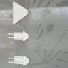 שלושה ווים לבנים, משולשים, צמודי קיר בקו אנכי על משטח זכוכית עם דוגמה פרחונית.